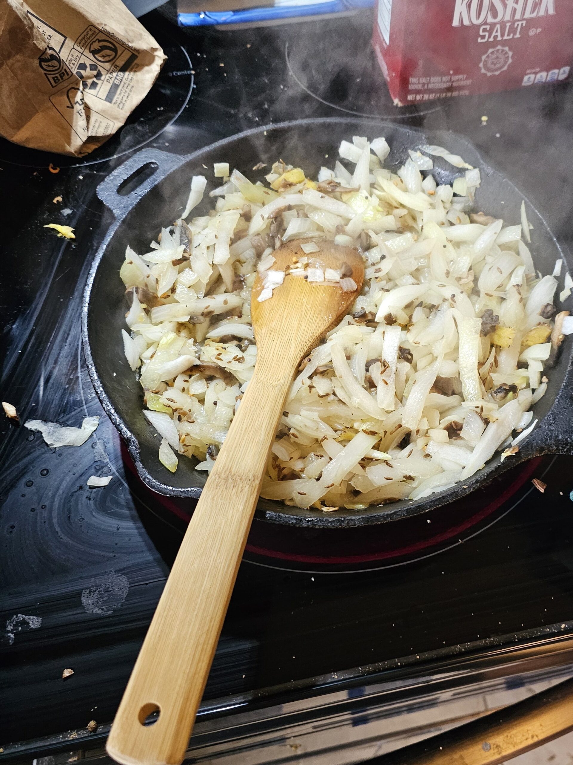 Sauteeing the onions, mushrooms, and ginger in a cast iron pan