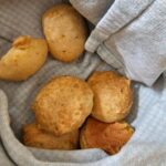 a towel lined basket with small cheese bread bites inside