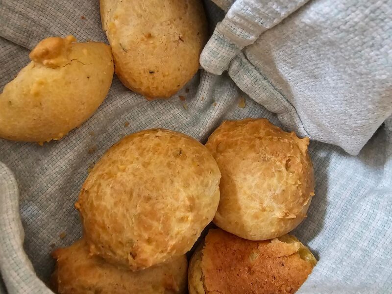 a towel lined basket with small cheese bread bites inside
