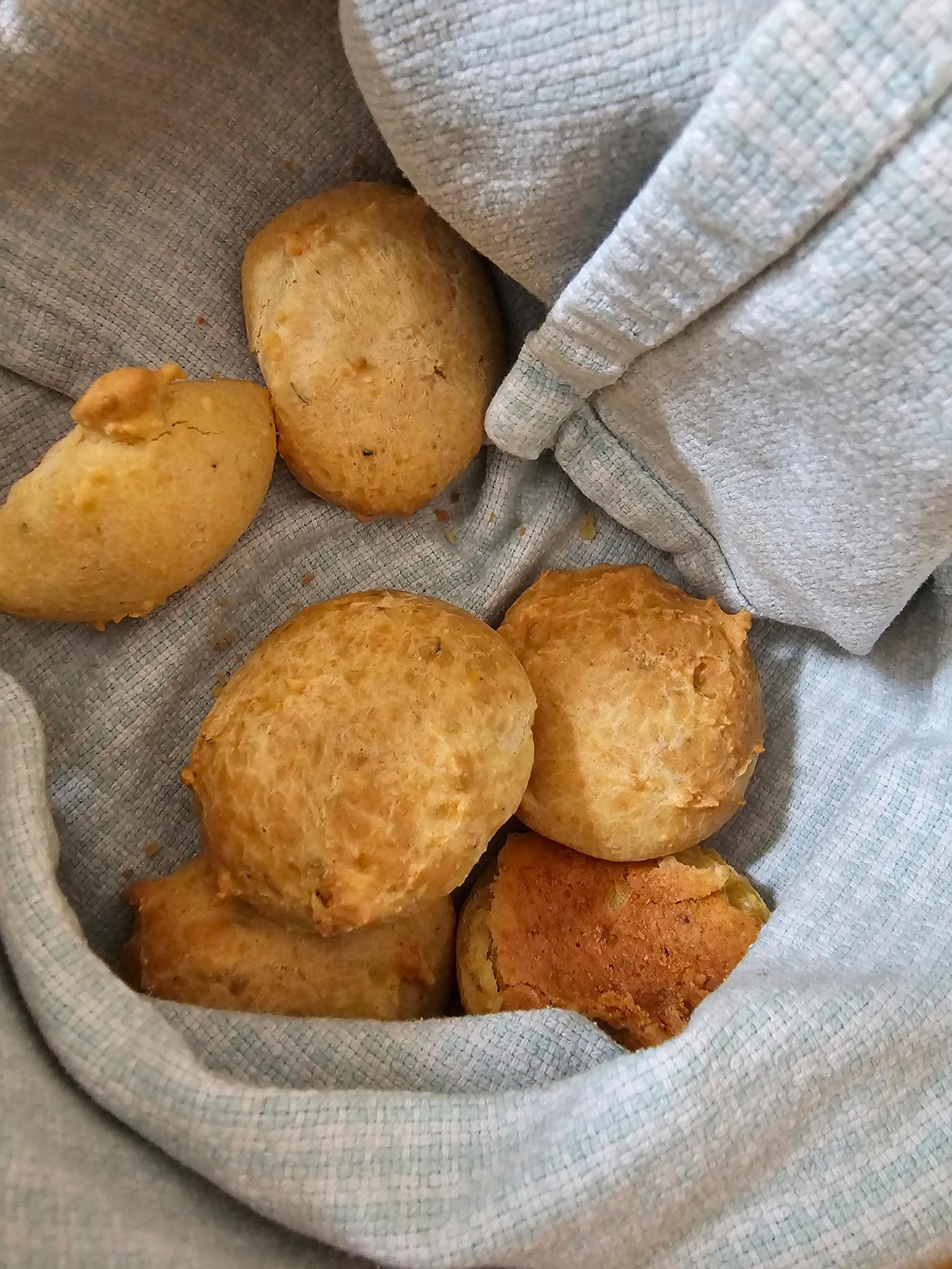 a towel lined basket with small cheese bread bites inside
